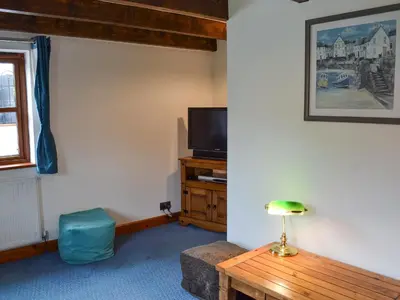 a living room with a tv and a wooden table at Bruce's Cottage in Saint Erth