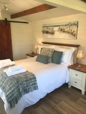 a bedroom with a large white bed and a wooden floor at Stargazy Garden in Hayle