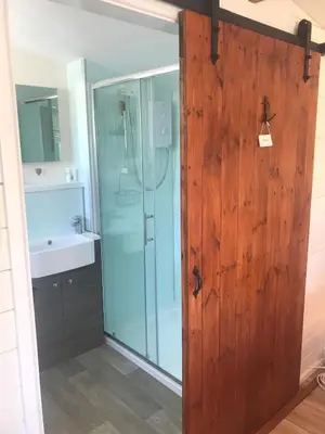 a bathroom with a shower and a glass door at Stargazy Garden in Hayle