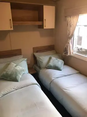 two beds in a small room with a window at Luxury Holiday Caravan Home in Newquay