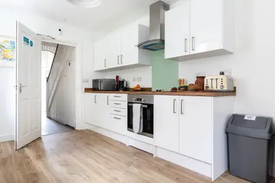 a kitchen with white cabinets and a wooden floor at Ocean House in St Ives