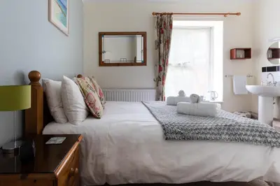 a bedroom with a bed and a mirror and a window at Ocean House in St Ives