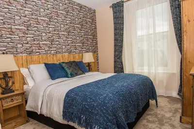 a bedroom with a large bed with a brick wall at Deluxe Rustic Charlestown Themed Apartment in St Austell