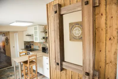 a sliding door into a kitchen with a table at Deluxe Rustic Charlestown Themed Apartment in St Austell