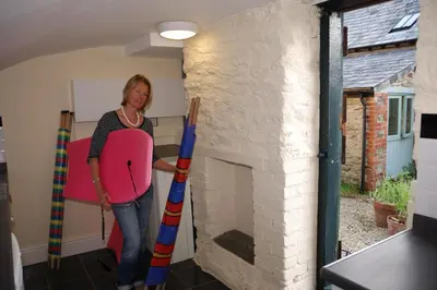 a woman standing in a room with a fireplace at Bowgie at Trewerry Cottages - Away from it all, close to everywhere in Newquay