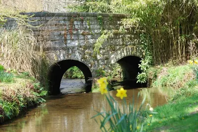 a stone bridge over a river with two tunnels at Bowgie at Trewerry Cottages - Away from it all, close to everywhere in Newquay