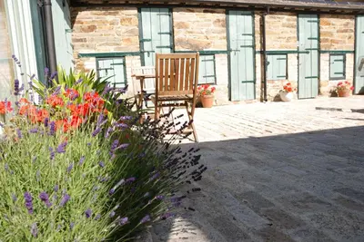 a wooden chair sitting on a patio with flowers at Bowgie at Trewerry Cottages - Away from it all, close to everywhere in Newquay
