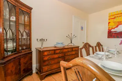 a dining room with a table and a china cabinet at 1 Dormer Villas in Porthscatho