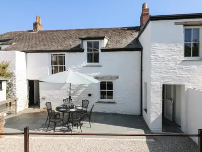a patio with a table and chairs and an umbrella at 1 Dormer Villas in Porthscatho
