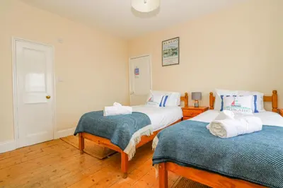 two beds in a room with wooden floors at 1 Dormer Villas in Porthscatho