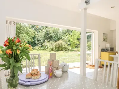 a dining room table with a vase of flowers and cookies at Little Chycoose in Truro