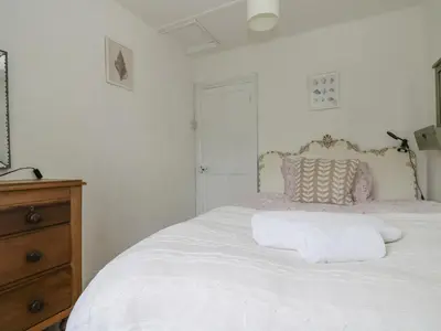 a bedroom with a white bed and a wooden dresser at Little Chycoose in Truro