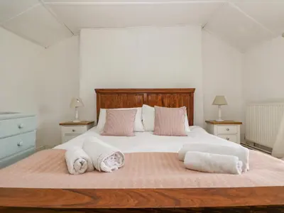 a bedroom with a large white bed with pink pillows at Little Chycoose in Truro