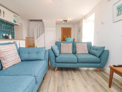 a living room with two blue couches and a table at Leghorn in St Austell