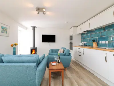 a living room with two blue couches and a table at Leghorn in St Austell