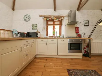 a kitchen with white cabinets and a clock on the wall at Courtyard in Porthleven