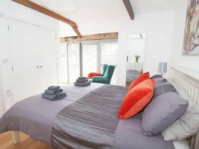 a bedroom with a bed with orange and gray pillows at The Old Dairy in Padstow