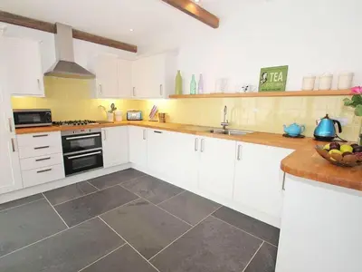 a kitchen with white cabinets and a sink and stove at The Old Dairy in Padstow