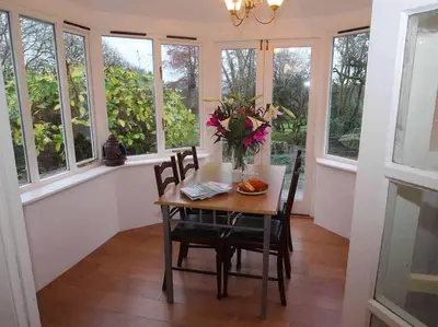 a dining room with a table and chairs and windows at Dairy Cottage in Bodmin