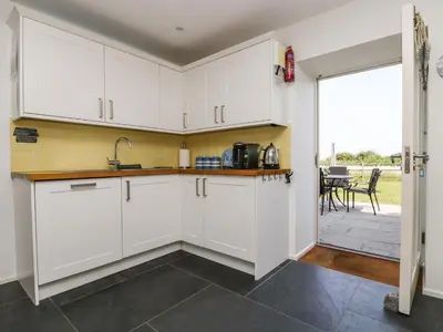 a kitchen with white cabinets and a view of a patio at Sundowner in Padstow