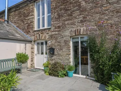 a brick building with a white door and a bench at Sundowner in Padstow