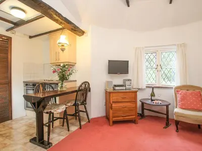 a living room with a table and chairs and a kitchen at Millstream in Tintagel