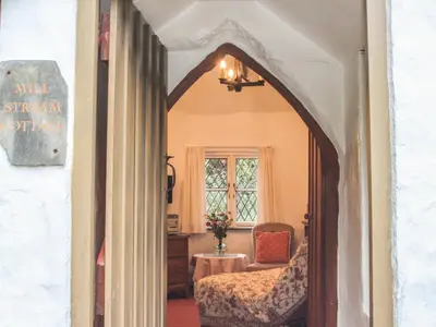 an archway leading into a room with a bed and a chair at Millstream in Tintagel