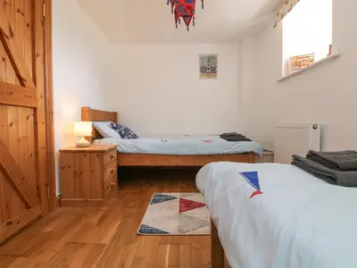 a bedroom with two beds and a wooden floor at Mill in Porthleven