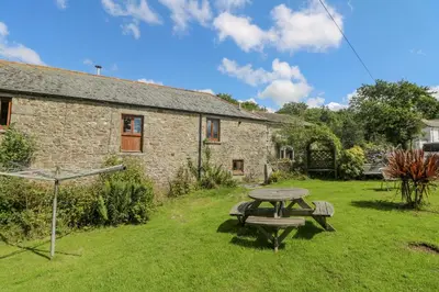 a picnic table in front of a stone building at Mill in Porthleven