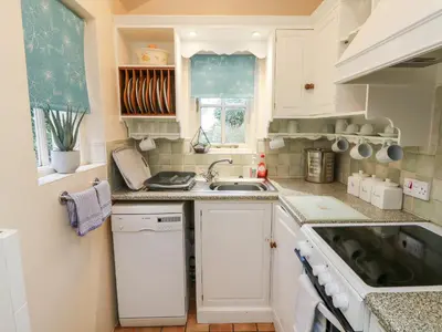 a small kitchen with white cabinets and a sink at Pippin in St Ives