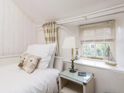 a white bedroom with a bed and a window at Pippin in St Ives