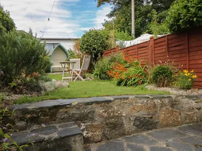 a garden with a retaining wall and a fence at Pippin in St Ives