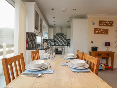 a dining room with a table with chairs and plates on it at Ocean Blue in Porthtowan