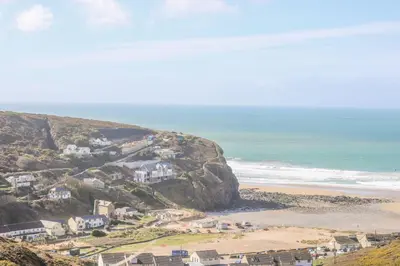 a group of houses on a hill next to a beach at Ocean Blue in Porthtowan