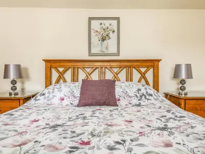 a bedroom with a bed with a floral bedspread and two lamps at Withan Farm Wing in Manaccan