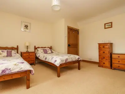 a bedroom with two beds and a dresser at Withan Farm Wing in Manaccan