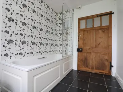 a bathroom with a white tub and black and white wallpaper at Withan Farm Wing in Manaccan