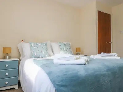a bedroom with a blue and white bed with towels on it at The Barn in Gunwalloe