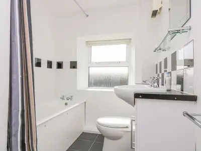 a white bathroom with a toilet and a sink at The Barn in Gunwalloe