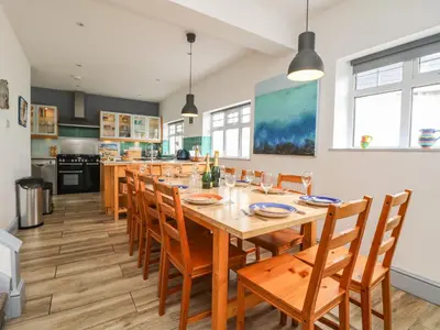a dining room with a large wooden table and chairs at Trelawns in Mawgan Porth