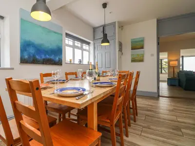 a dining room with a wooden table and chairs at Trelawns in Mawgan Porth