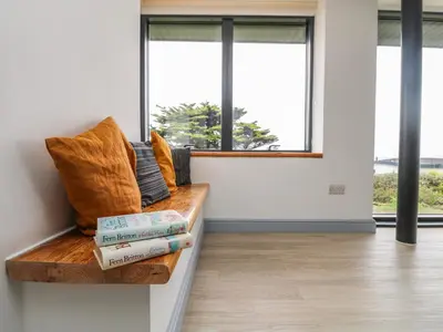 a room with a bench with books and windows at Trelawns in Mawgan Porth