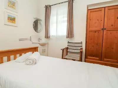 a bedroom with a bed and a chair at Trelawns in Mawgan Porth