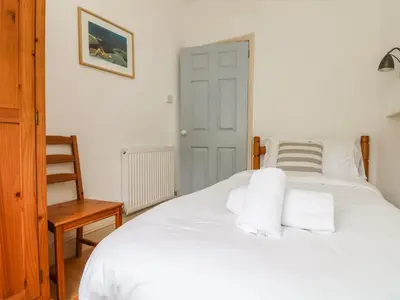 a bedroom with a white bed with white pillows at Trelawns in Mawgan Porth