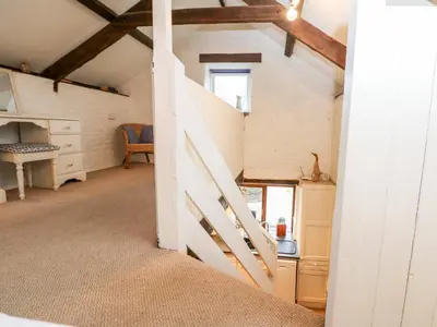 an attic room with a staircase and a desk at Apple Loft in Lostwithiel