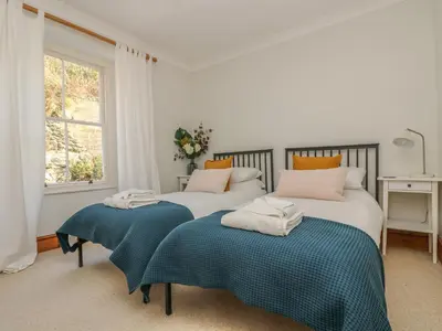 two beds in a white room with a window at Haven in Helston