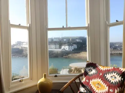a room with three windows looking out at the water at Haven in Helston
