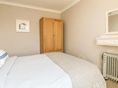 a bedroom with a bed and a wooden cabinet at Haven in Helston