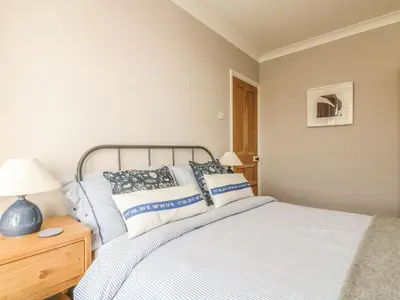 a bedroom with a bed and a lamp on a night stand at Haven in Helston