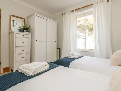 a bedroom with two beds and a dresser and a window at Haven in Helston